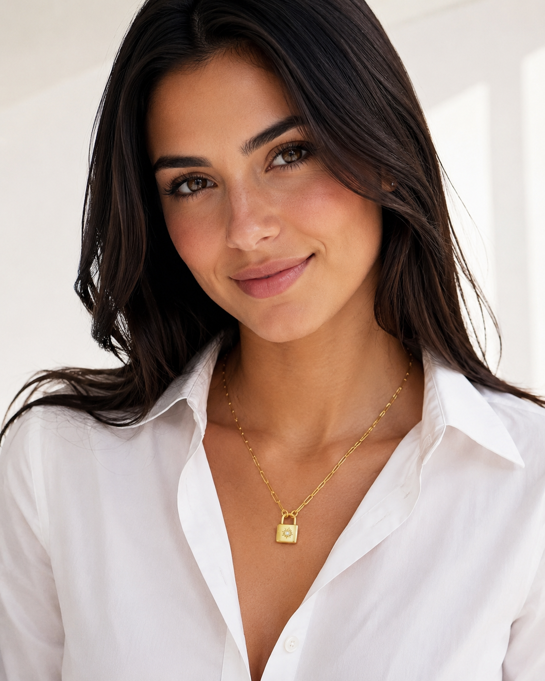 Model wearing the Charlotte gold locket necklace with a white collared shirt and sleek dark hair