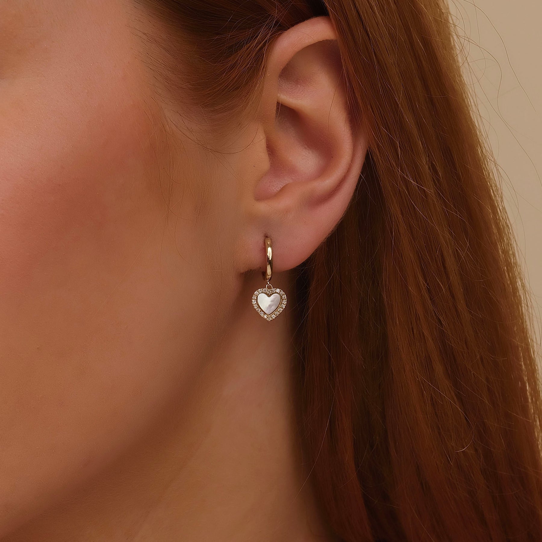 Model wearing Gigi mother of pearl heart drop hoop earrings