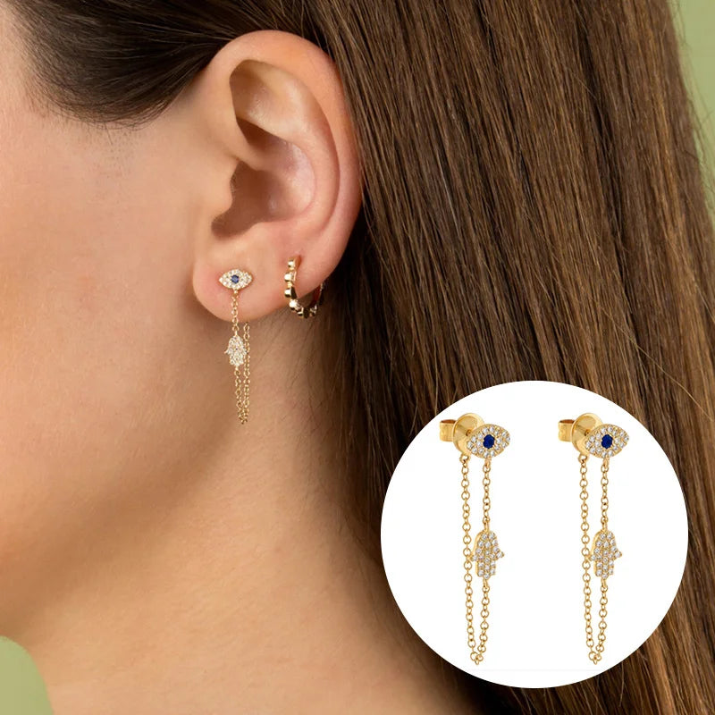 Model wearing Bianca gold evil eye and hamsa chain drop earrings