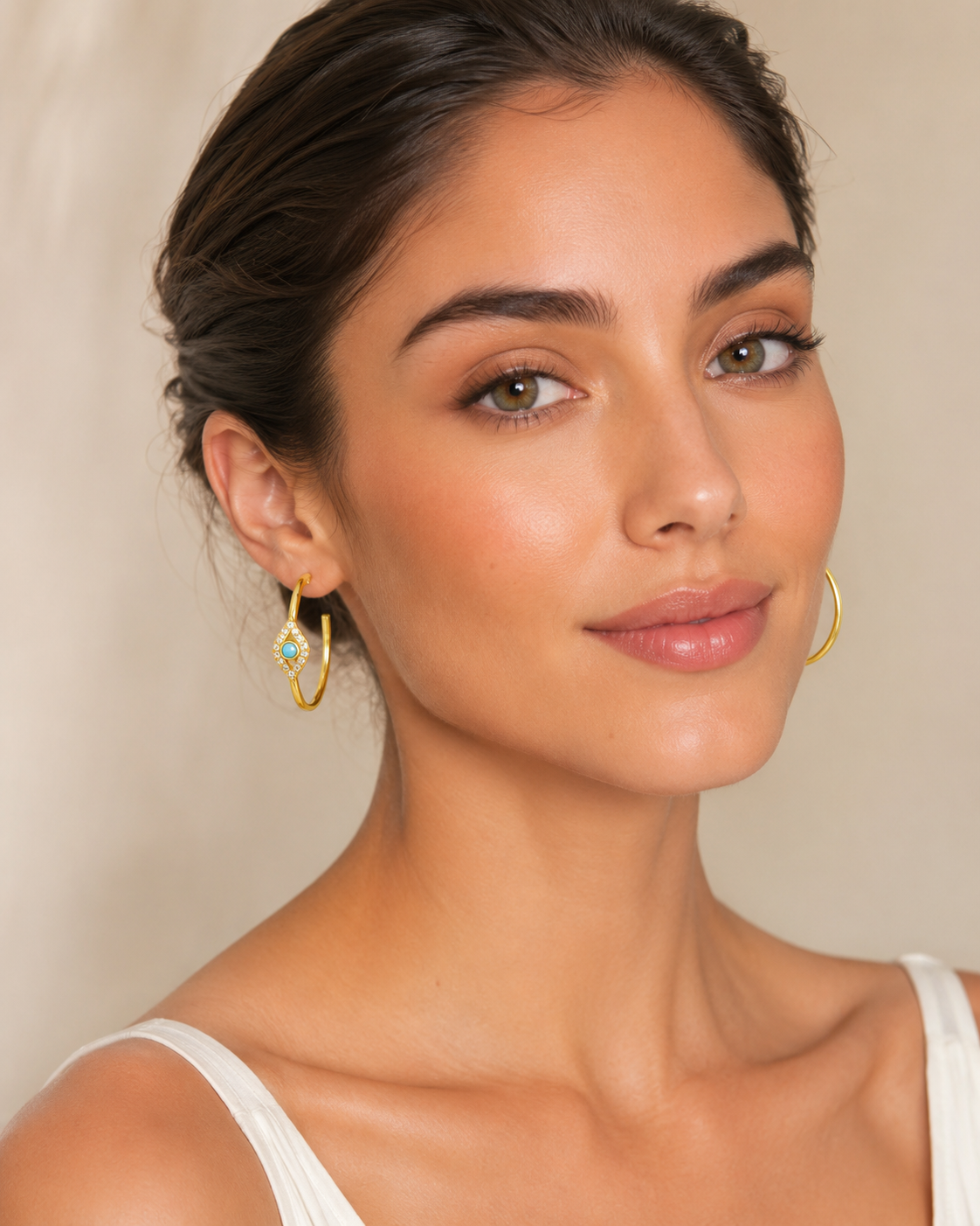 Model wearing Monica gold evil eye hoop earrings with turquoise stones
