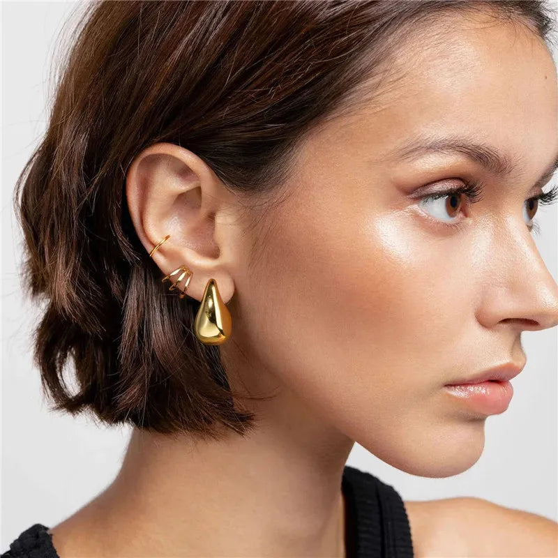 Side-profile view of a woman wearing the Terry gold teardrop statement earring